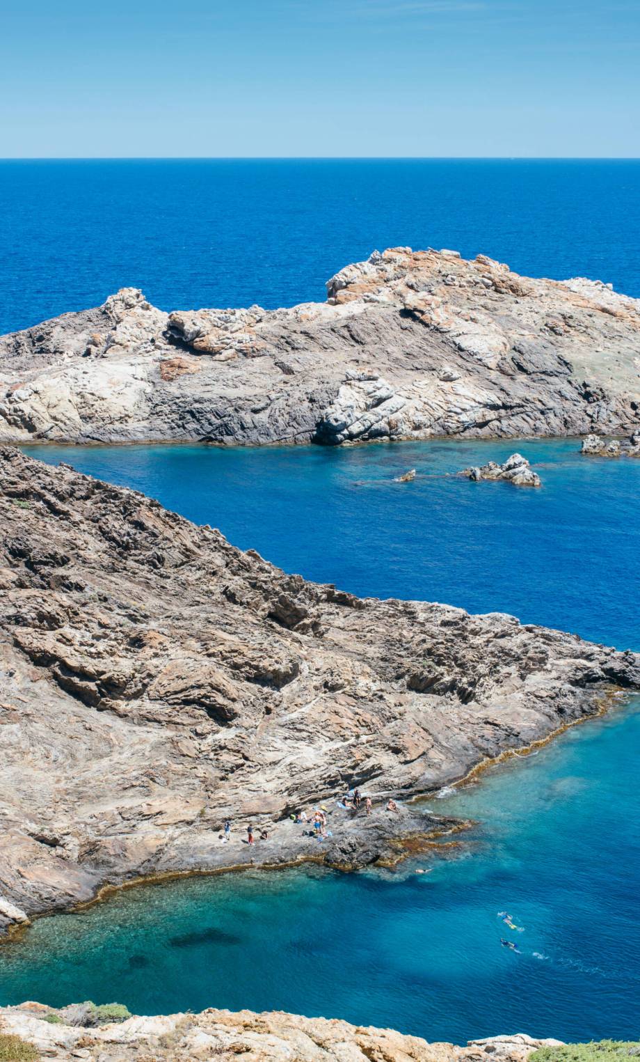 Vertical outdoors shot of big rocks placed at blue peaceful ocean.