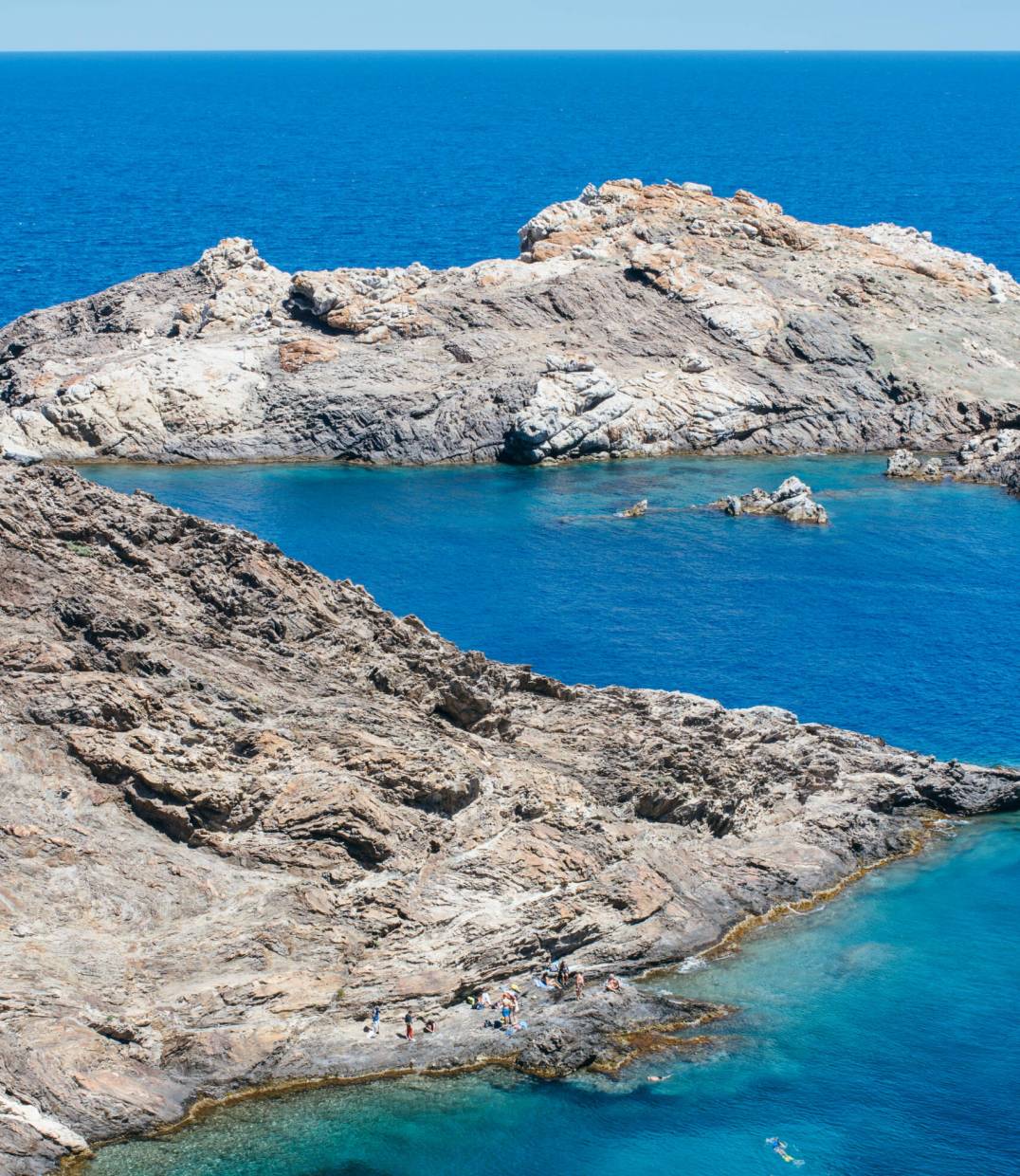 Vertical outdoors shot of big rocks placed at blue peaceful ocean.